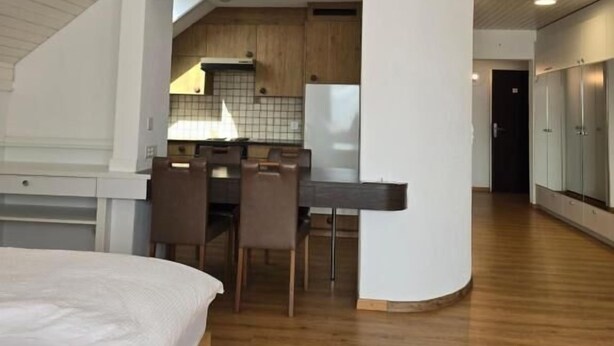 Un dormitorio tipo loft moderno con una cama grande, un comedor y una cocina al fondo.