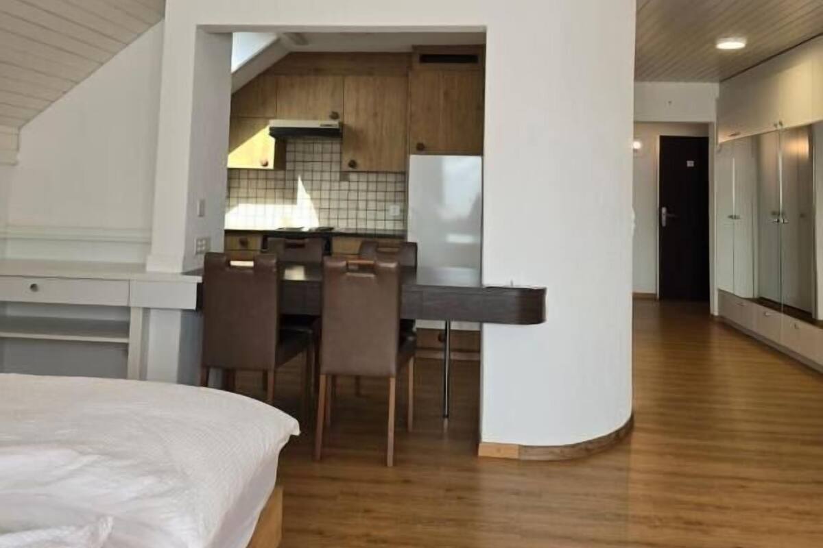 Une chambre de style loft moderne, avec un grand lit, un coin repas et une cuisine en arrière-plan.