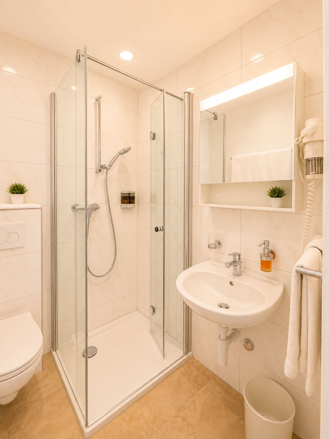 Ein modernes Badezimmer mit einer gläsernen Duschkabine, einem weißen Waschbecken und einem Spiegel darüber.