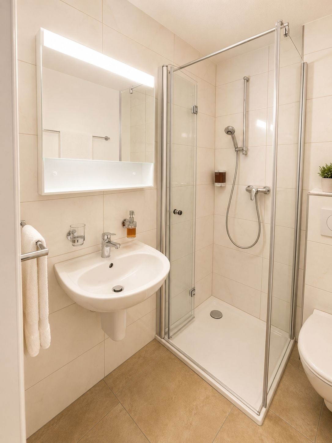 Ein modernes Badezimmer mit einer in Glas eingefassten Dusche, einem weißen Waschbecken und einem Spiegel darüber.