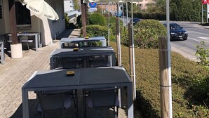Mesas y sillas al aire libre bajo sombrillas con el nombre de marca 'VALSER'.