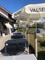 Mesas y sillas al aire libre bajo sombrillas con el nombre de marca 'VALSER'.