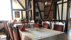 Comedor con una mesa larga dispuesta para seis, sillas de madera con cojines a rayas verdes y rojos, y un mantel blanco.