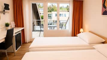 Ein Hotelzimmer mit zwei Betten, einem Schreibtisch, einem Stuhl und Blick ins Freie.