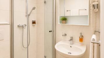 A modern bathroom with a glass-enclosed shower, a white sink, and a mirror above the sink.