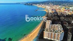 Une vue aérienne d’une ville côtière, avec une plage, des bâtiments et une mer bleue et limpide.