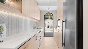 Eine moderne Küche mit Holzausbau, einer Marmorarbeitsplatte und einem Edelstahlkühlschrank.