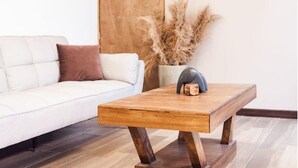 Una sala de estar moderna con un sofá blanco, una mesa de centro de madera y un jarrón con plantas secas.