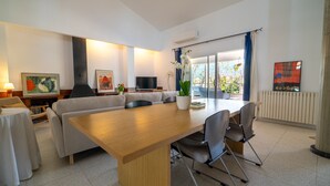 A modern living room with a sofa, a dining table, chairs, a TV, and artwork on the walls. - Rostoll Espai de Calma (Muro)