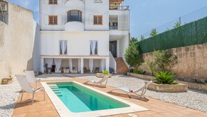 A two-story building with a swimming pool, outdoor seating, and a garden area. - Rostoll Espai de Calma (Muro)