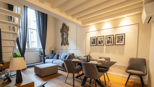 Un salon moderne comprenant un canapé, une table à manger, des chaises et un escalier.