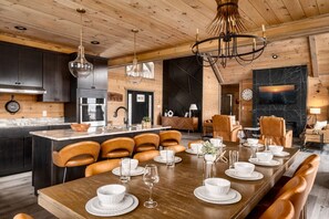 Una cocina moderna con armarios de madera, una isla central y un comedor con sillas de cuero y una mesa de madera preparada para una comida.