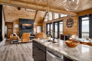 Een ruime keuken met een groot eiland, houten wanden en een eethoek met stoelen.