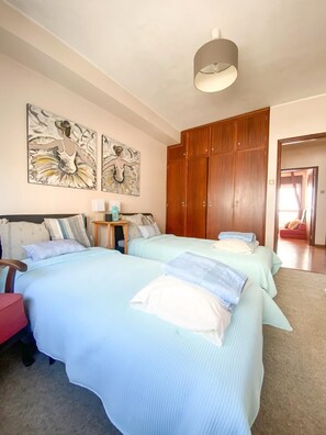 Ein Schlafzimmer mit zwei Betten, einem Holzschrank und zwei Wandbildern.