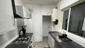 A modern kitchen with white cabinets, a black countertop, and a gas stove.