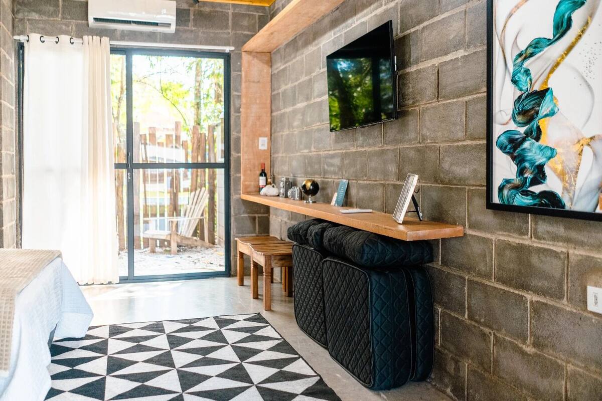 A modern room with a bed, a desk, and a TV mounted on the wall.