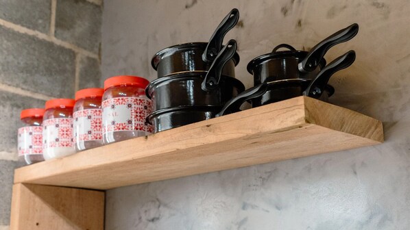 Une étagère en bois avec des pots et des bocaux noirs, dotés de couvercles rouges.