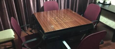 Un salón de conferencias con una mesa de madera, cuatro sillas rojas, una mesita auxiliar y un telón de fondo.