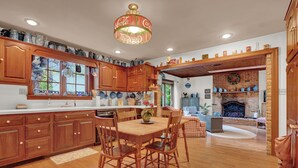 A spacious kitchen with wooden cabinets, a dining table, and a brick fireplace.