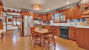 A spacious kitchen with wooden cabinets, a stainless steel refrigerator, and a dining area with a wooden table and chairs.