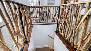 Eine Treppe mit einem einzigartigen Geländer aus Holz, Teppichstufen und Blick ins Freie.