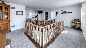 Ein geräumiger Wohnbereich mit einer zentralen Holzkonstruktion, einer Küche im Hintergrund und einem Essbereich mit Tisch und Stühlen.