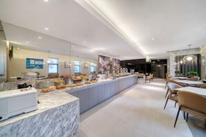 A modern hotel lobby with a marble reception desk, a buffet area with various food items, and a seating area with tables and chairs. - JJ Hotel (Shanghai Nanxiang Guyi Garden Branch) (Shanghai)