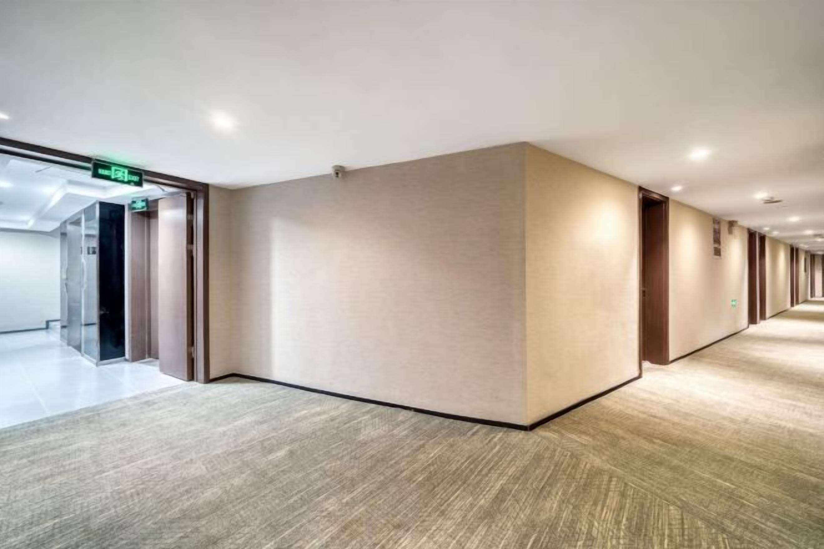 A long, narrow hallway with beige walls and a carpeted floor.