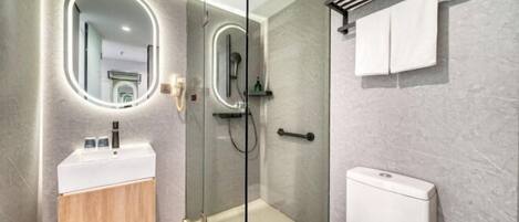 Un baño moderno con ducha envuelta en vidrio, un lavamanos blanco y un inodoro.