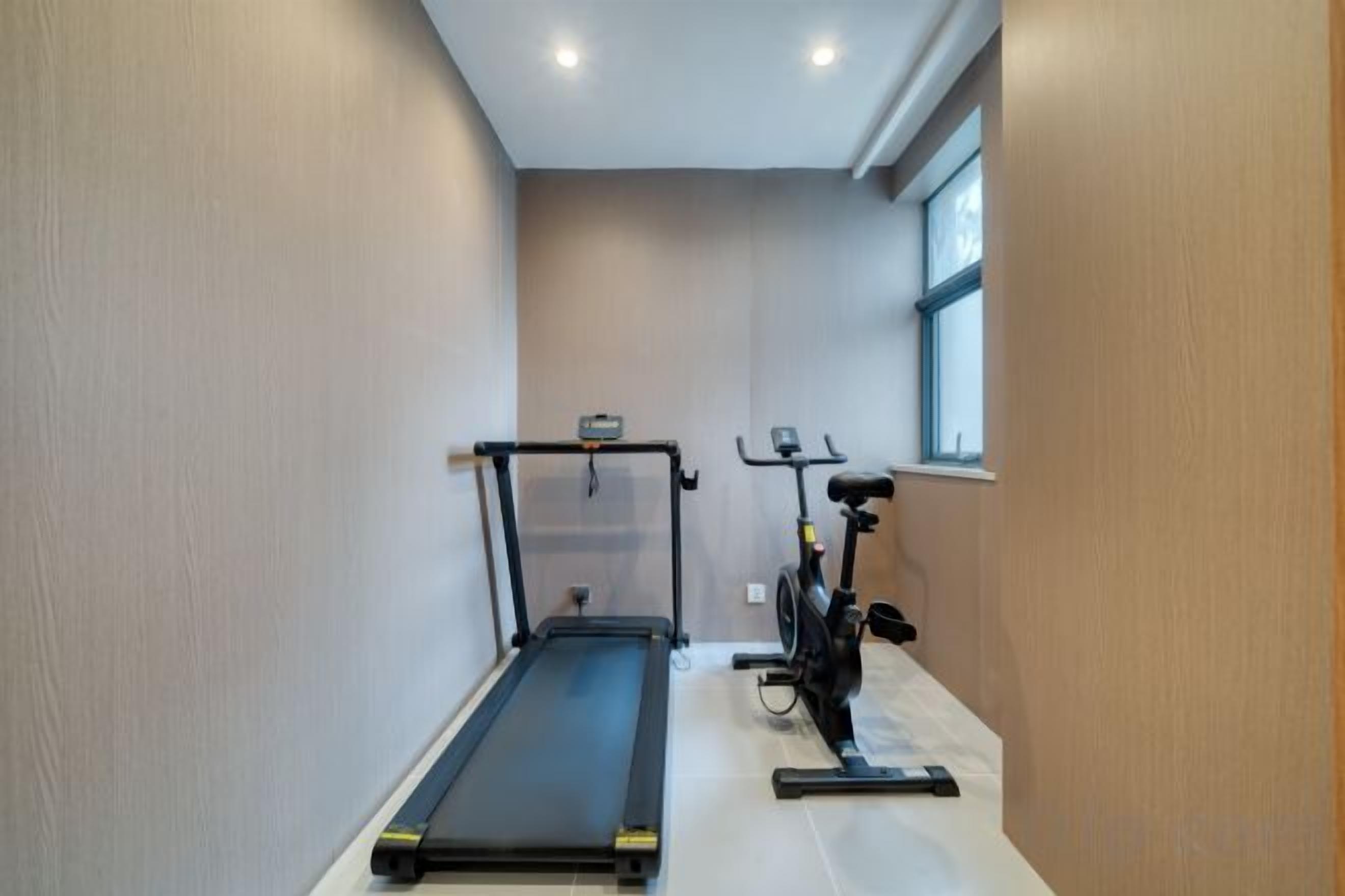 A narrow hallway with a treadmill and an exercise bike.