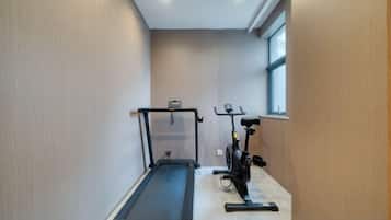 A narrow hallway with a treadmill and an exercise bike.