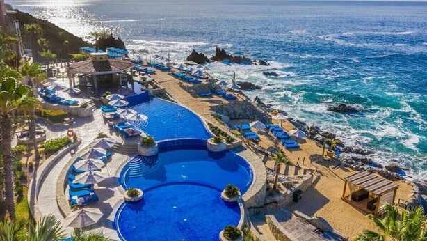 Ein Resort mit großem Pool, Liegestühlen und Blick auf den Ozean.