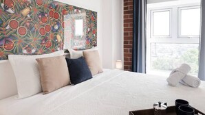 A hotel room with a large bed, a colorful abstract painting on the wall, a window with a view, and a tray with a coffee pot and two cups. - 3 bd in zona 2 (Ciudad de Guatemala)