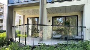 Een modern gebouw met een glazen balkon, zitplaatsen buiten en een gevel van baksteen.