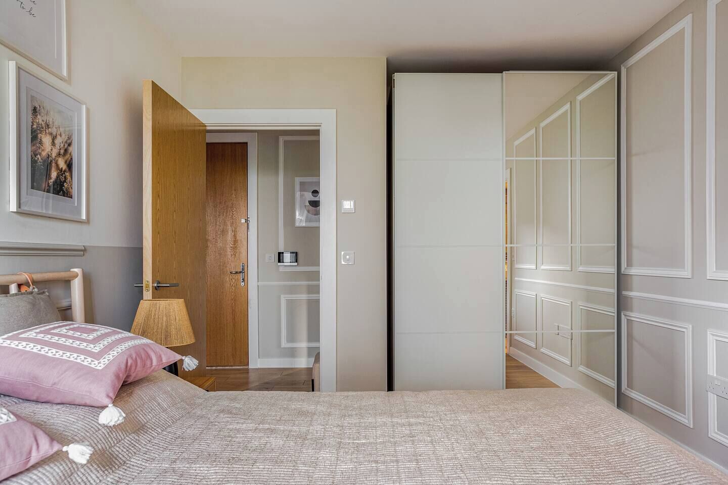 A bedroom with a bed, a wooden door, a wardrobe, and a framed picture on the wall.