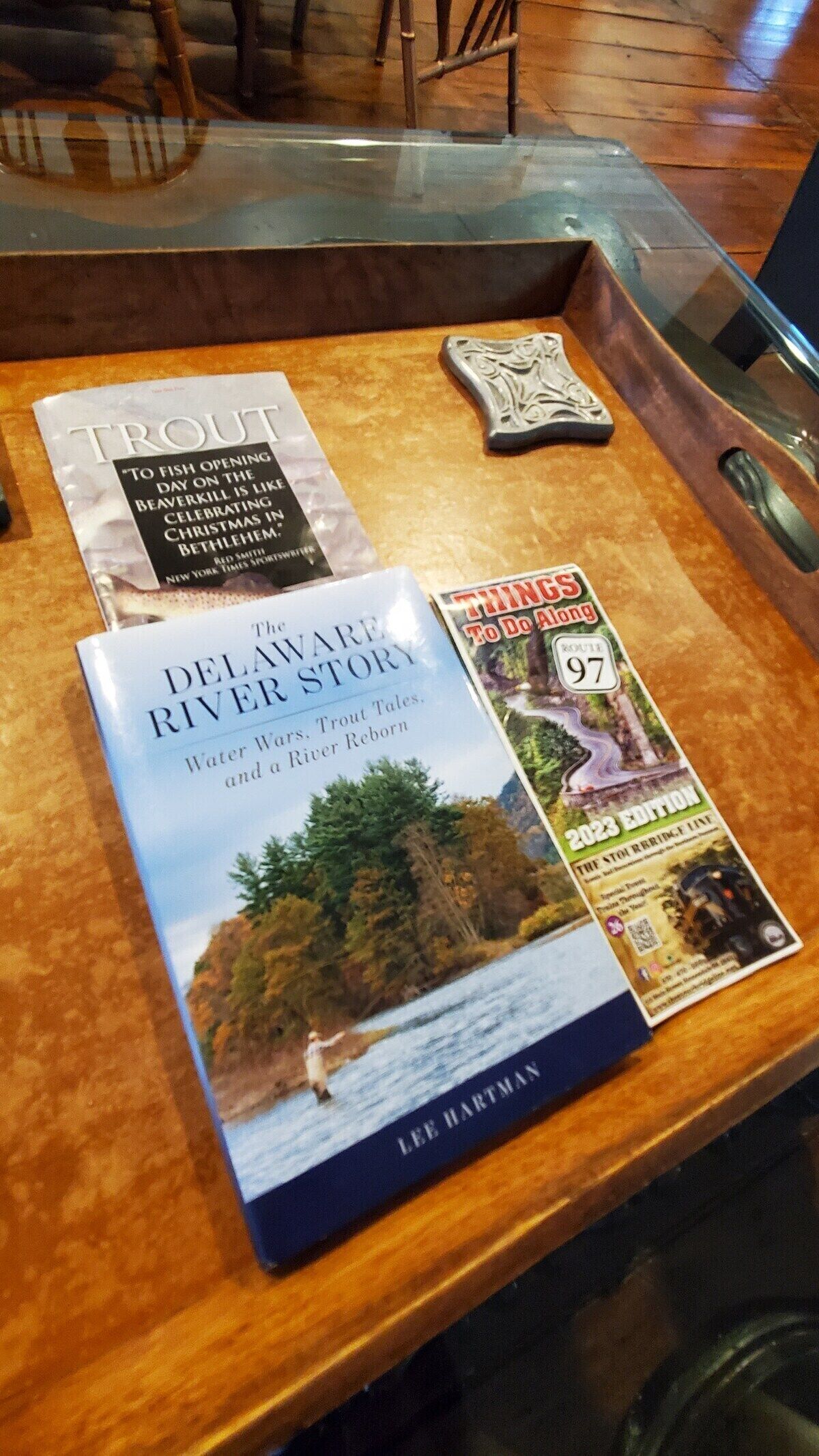 A wooden table with three books: 'The Delaware River Story' by Lee Hartman, 'Troll' by Red Smith, and 'Things to Do Along the Delaware River' 97th edition.