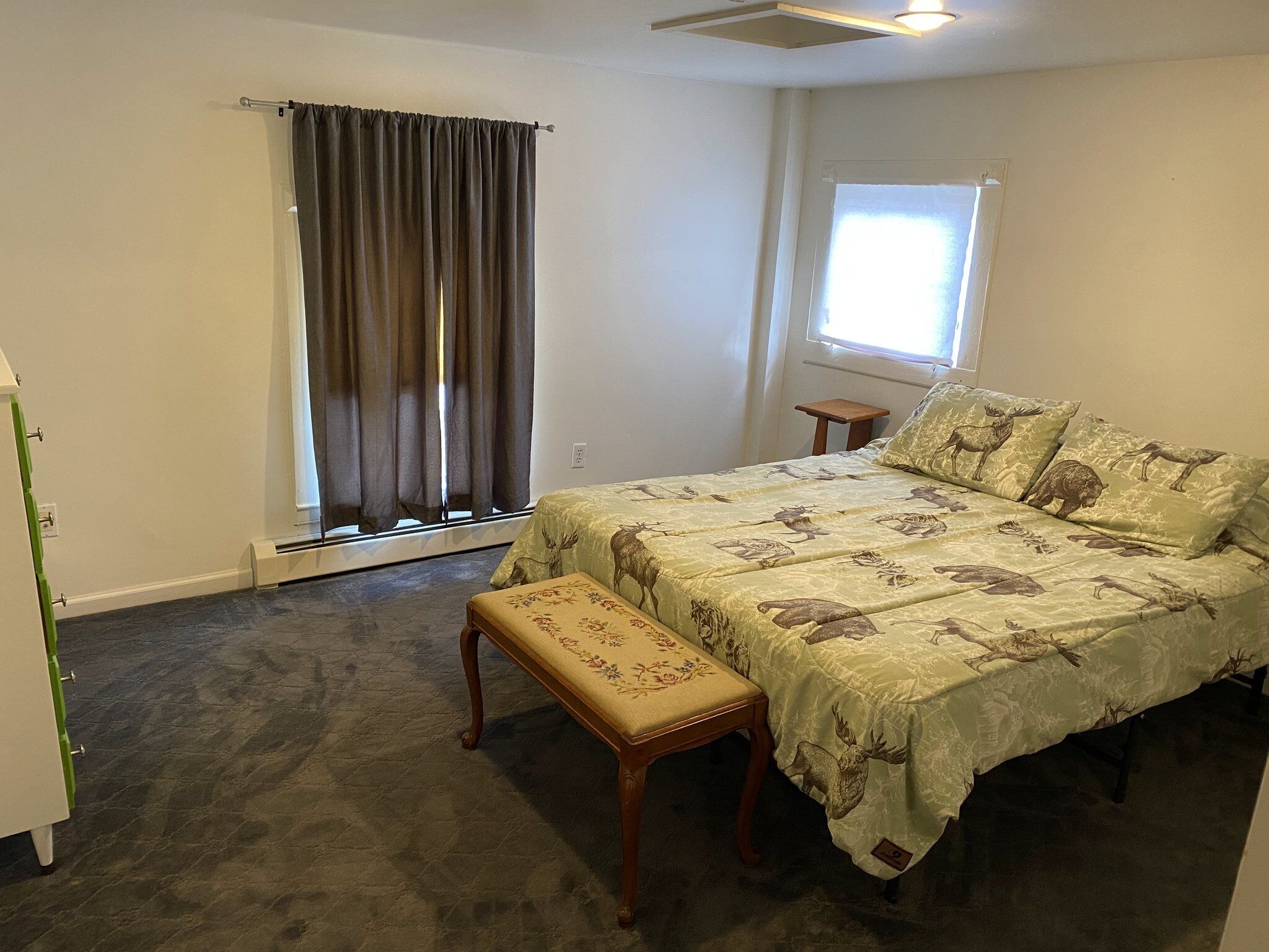 A bedroom with a bed, a bench, a window, and a door.