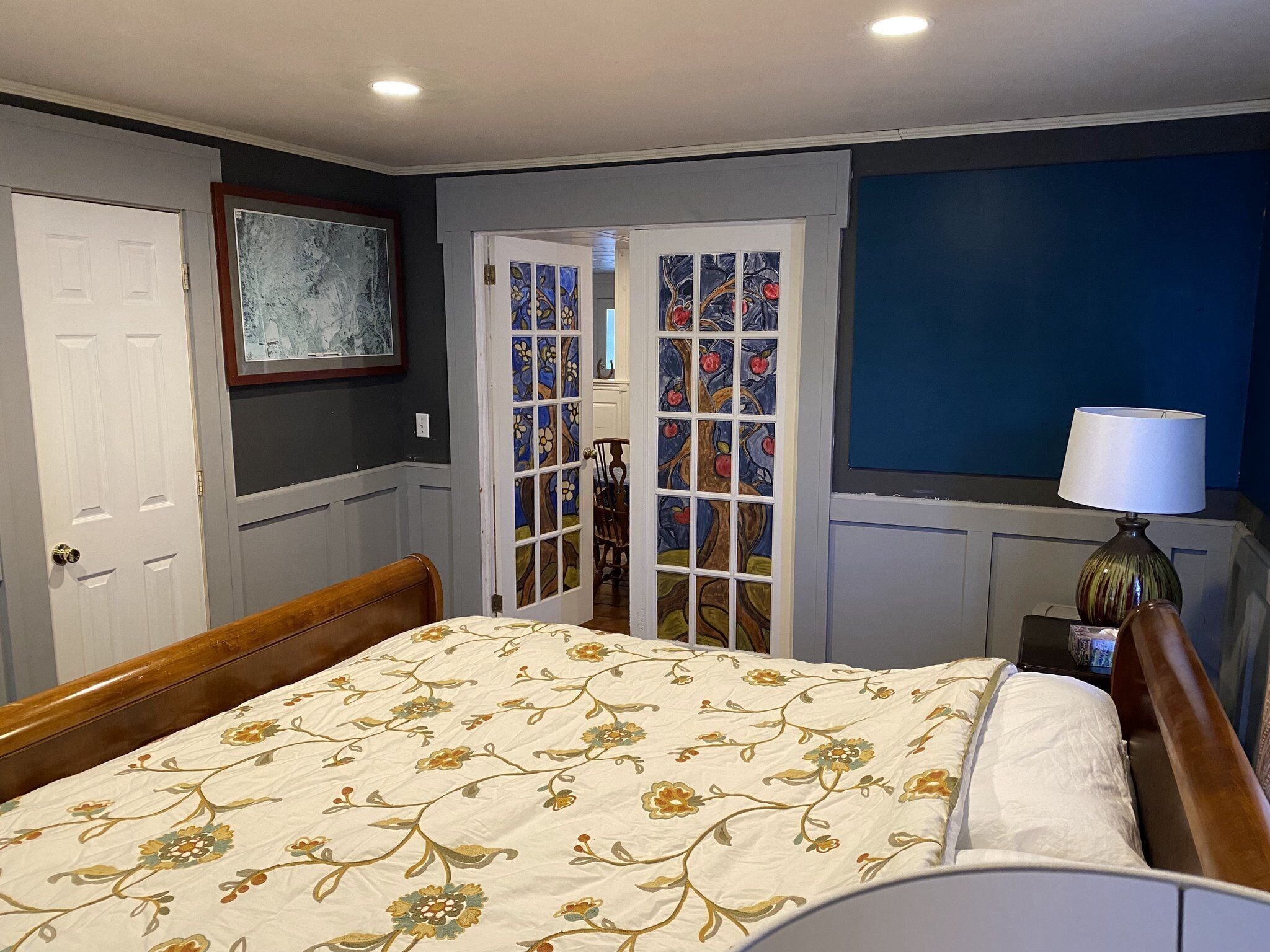 A bedroom with a bed, a door, a window, and a lamp.