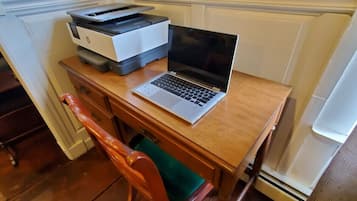 A wooden desk with a laptop, a printer, and a chair.