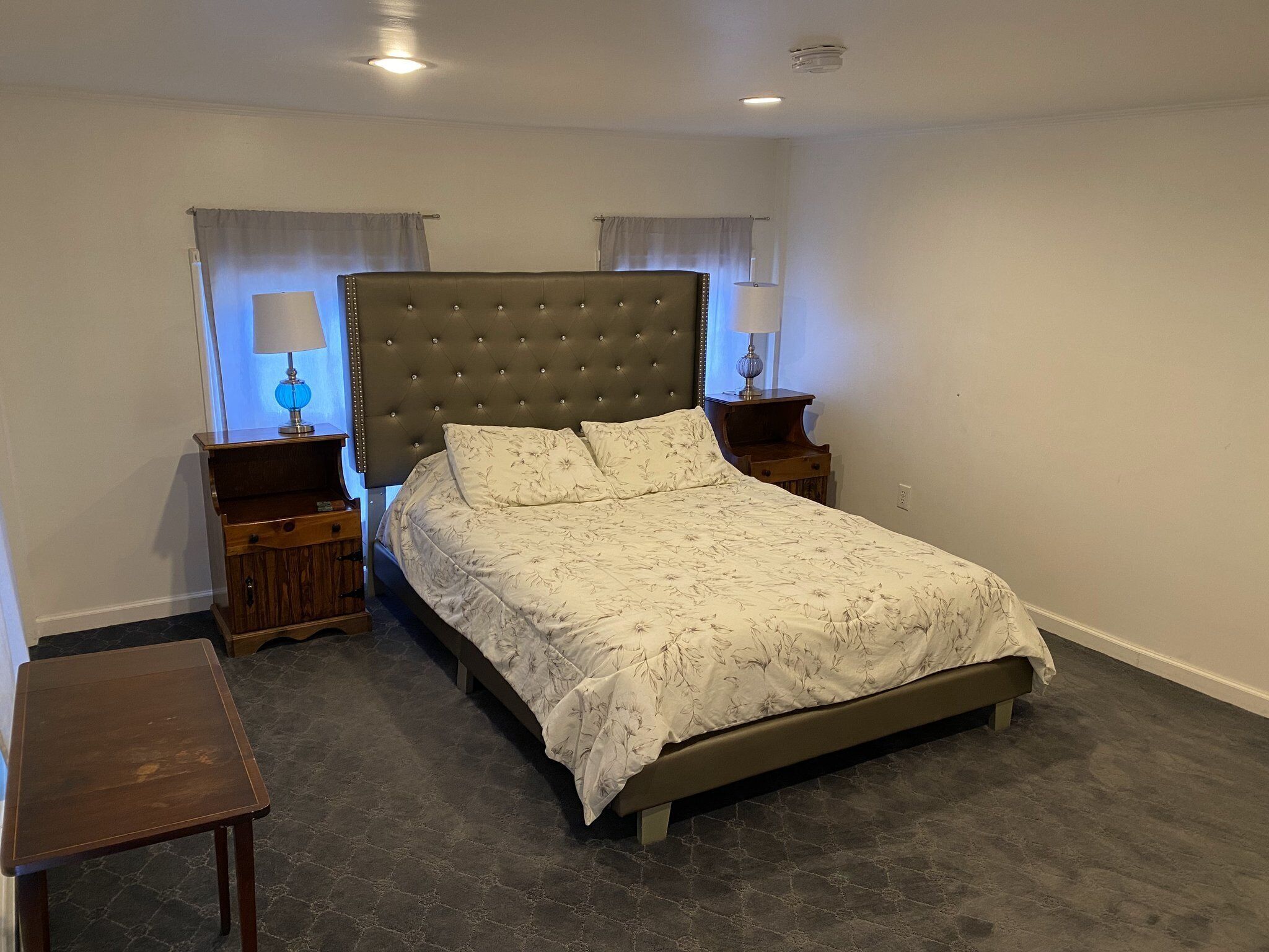 Ein Schlafzimmer mit einem Bett, zwei Nachttischen, einem Beistelltisch und einem kleinen Holztisch.
