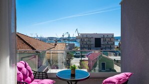 A balcony with a table and chairs, overlooking a marina with boats and buildings. - Seaview apartment Lana (Seget Donji)
