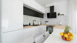 A modern kitchen with white cabinetry, a wooden countertop, a built-in oven, and a black range hood. - Seaview apartment Lana (Seget Donji)