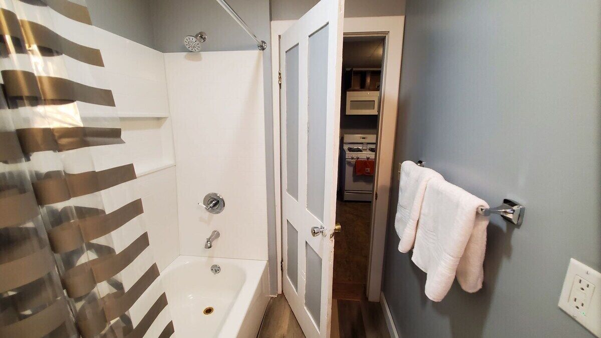A bathroom with a bathtub, a shower, and a towel rack.