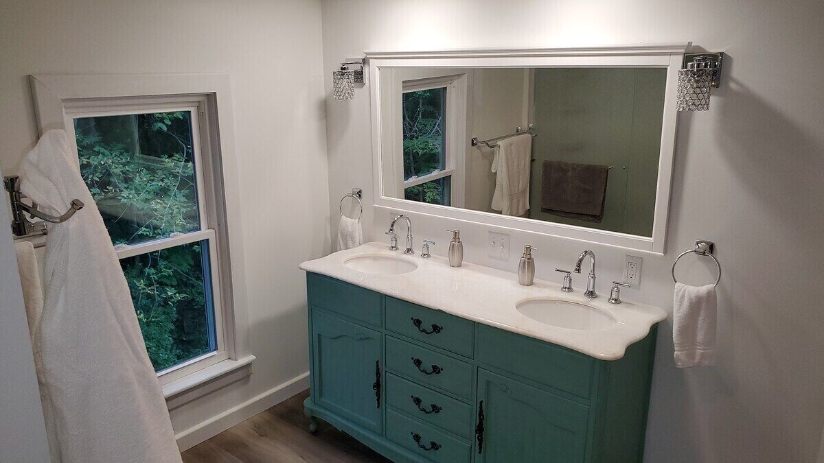 A bathroom with a double sink vanity, a large mirror, and a window.