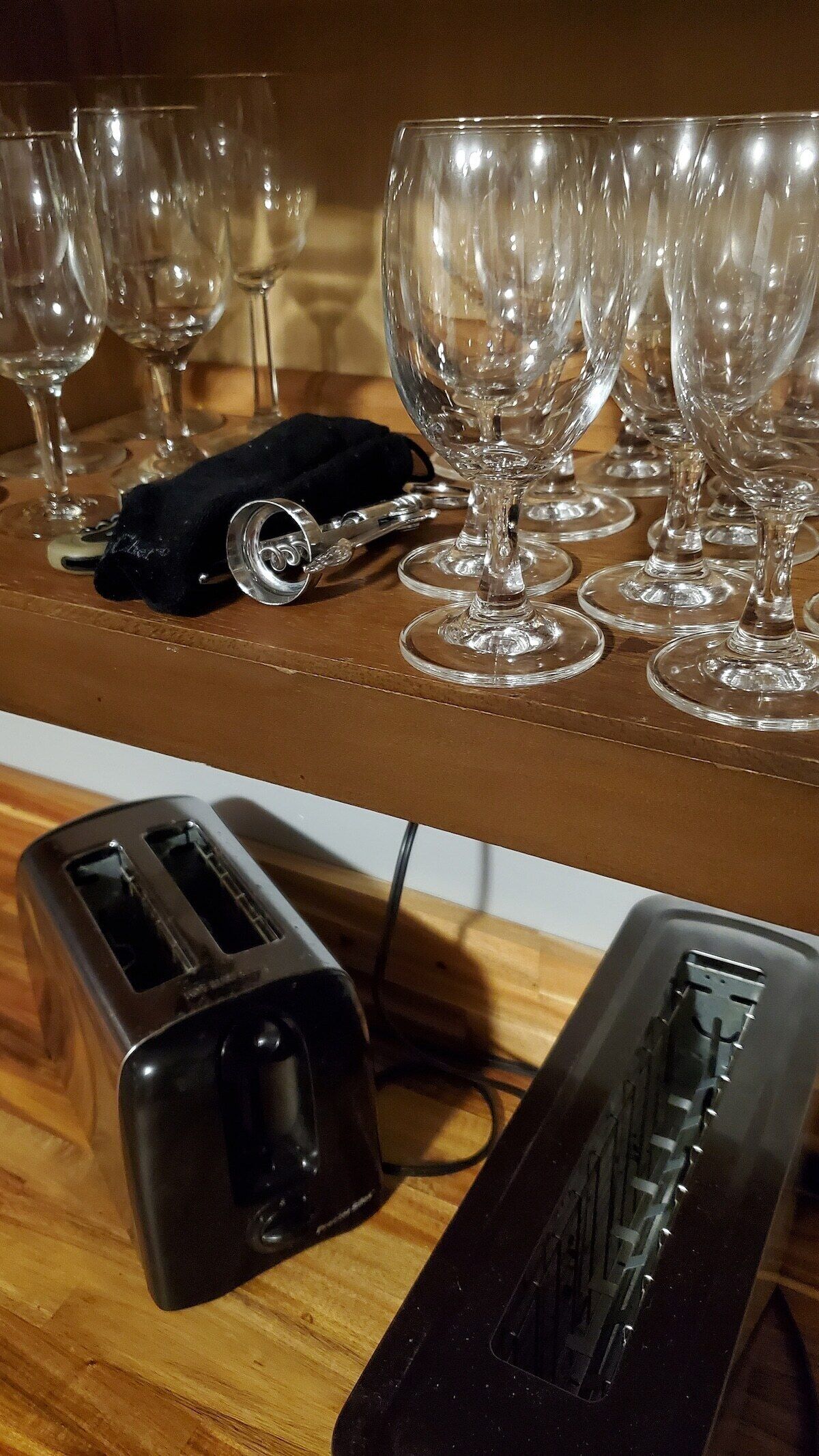 A kitchen counter with multiple wine glasses and a toaster.