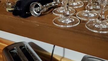 A kitchen counter with multiple wine glasses and a toaster.