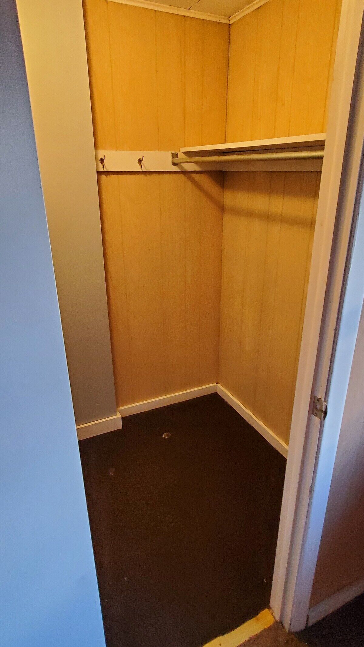 Una piccola armadiatura chiusa con pareti in legno e pavimento scuro.