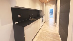 Une cuisine moderne avec des plans de travail noirs, des armoires blanches et un plafond en bois.