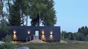 Un bâtiment moderne aux couleurs sombres, doté d’une façade symétrique, d’une entrée centrale et d’un escalier menant à la porte.