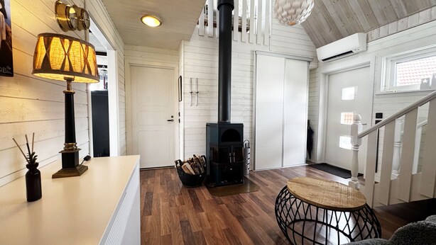 A modern interior with a wood-burning stove, a staircase, and a dining area.